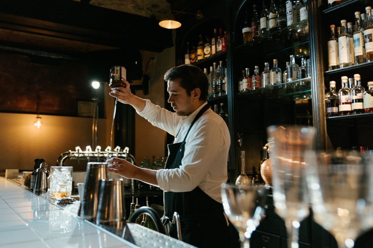 Bartender pouring alcohol into jigger for precise measurement